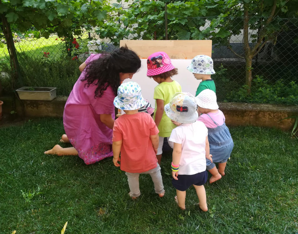 i bambini insieme all'educatrice in giardino mentre pitturano