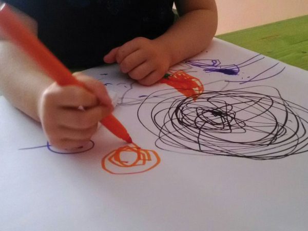 un bambino mentre disegna con i colori su un foglio